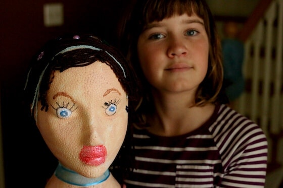 girl holding styrofoam head painted to look like herself