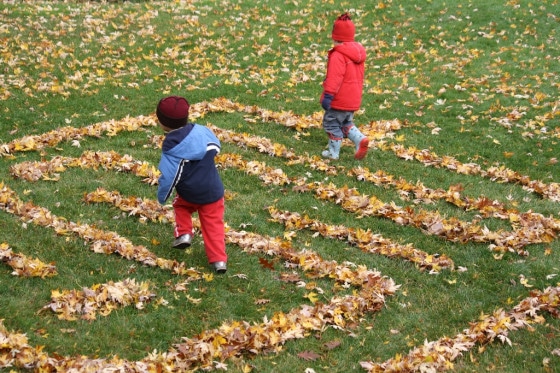 toddler and preschooler running through leaf maze