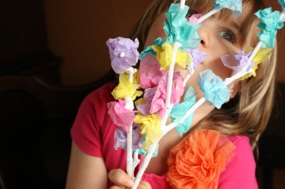 Child holding tissue paper blossom tree craft