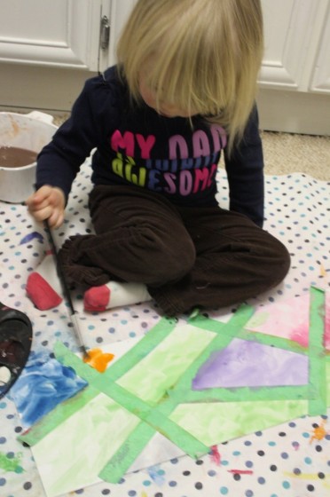 2 year old sitting on the floor, painting