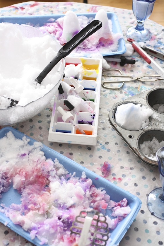 table scattered with supplies for colouring the snow