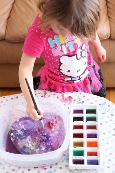 preschooler painting an ice heart with rock salt and watercolours