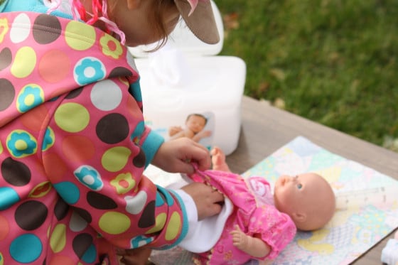 close up of preschooler diapering a doll