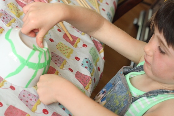 Child putting painter's tape on a white bowl