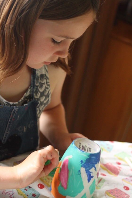 child removing painters tape from painted mug