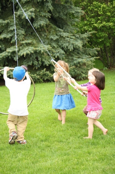 4 kids gathered around a hoola hoop and rope activity