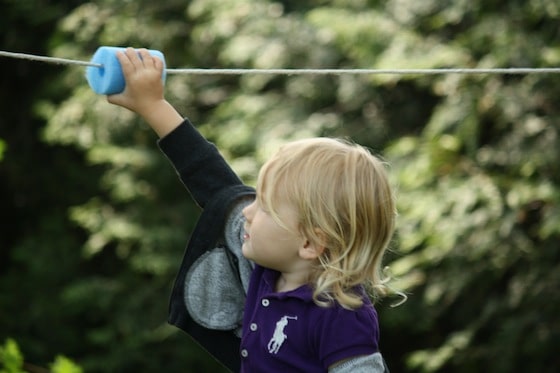 toddler sliding piece of pool noodle on rope