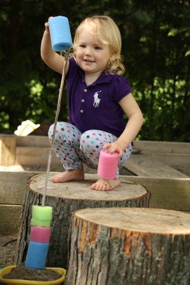 toddler stacking pool noodle pieces on stick