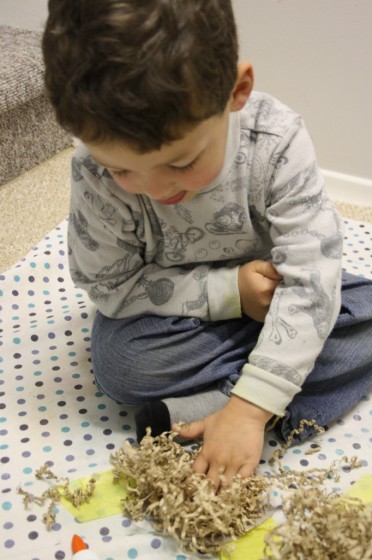 preschooler making paper nest