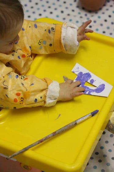 baby finger painting on cardboard letter A