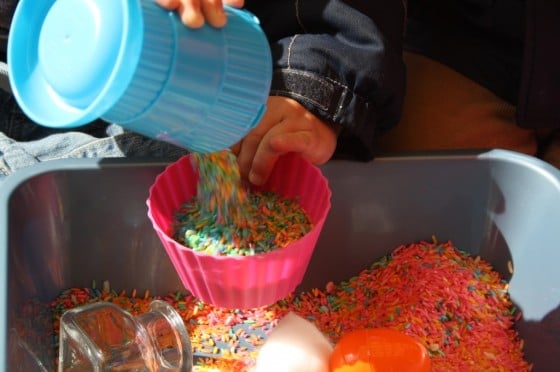 child pouring rice into pink bowl