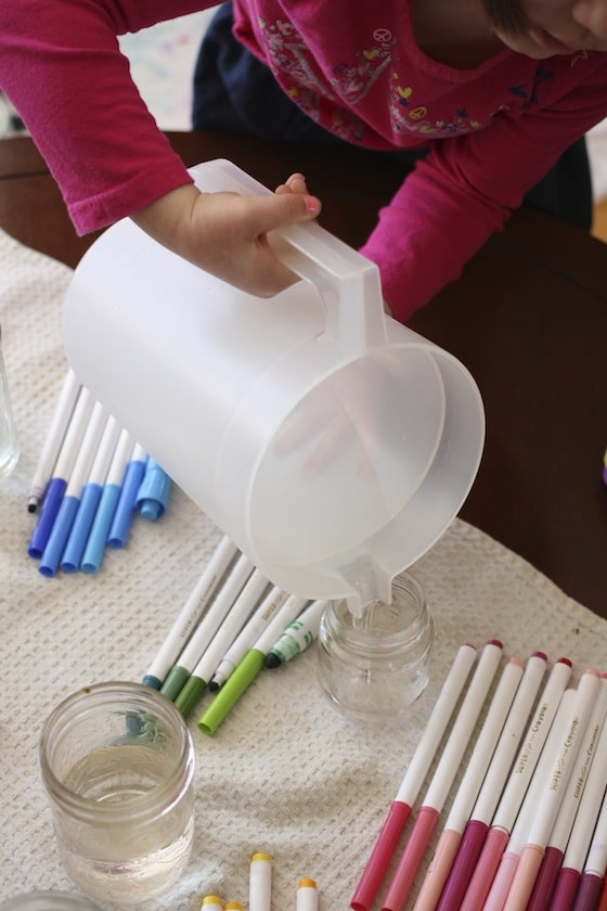 Pouring water into our jars to make our homemade liquid watercolour paints.