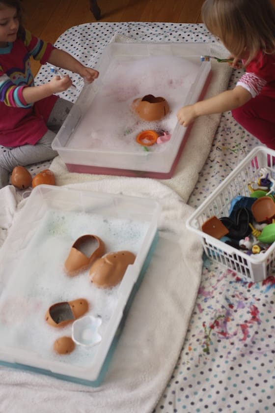 preschoolers washing toys in bins of soapy water