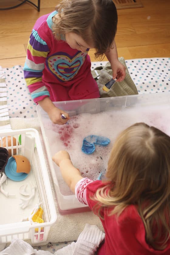 preschoolers washing potato heads in soapy water bin 