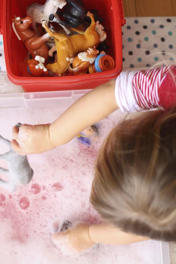 Kids washing toys in basin of soapy water