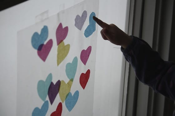 sticking tissue paper hearts to contact paper on a window