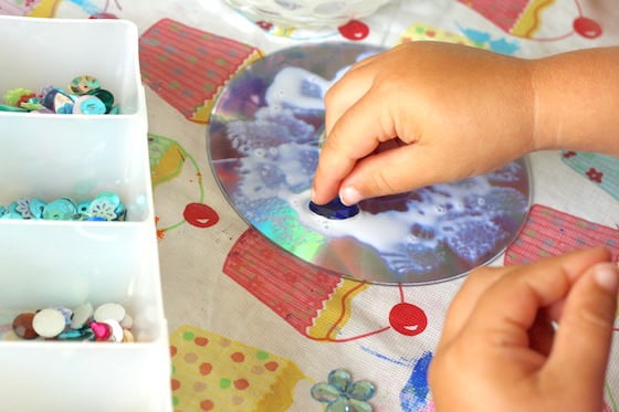 child gluing craft gems to cd