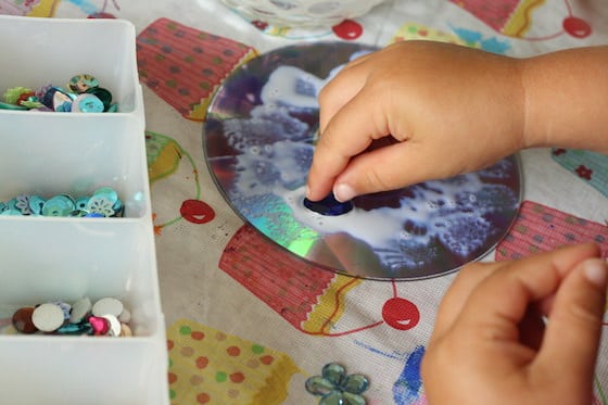 Child gluing gems to a cd