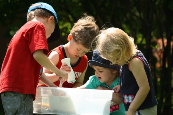 kids gathered around a sensory bin of ice and salt and water