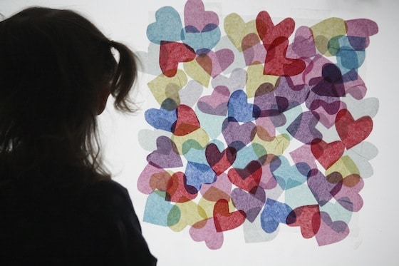 child admires her tissue paper, stained glass window