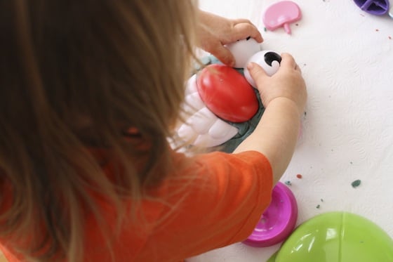 Adding Potato Head eyes to a play dough head.