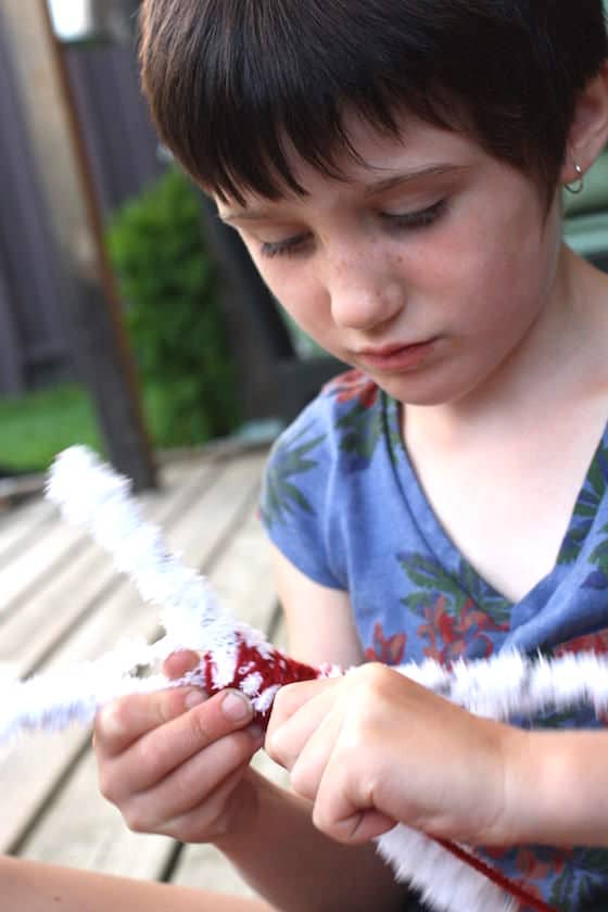 child wrapping twigs with yarn 