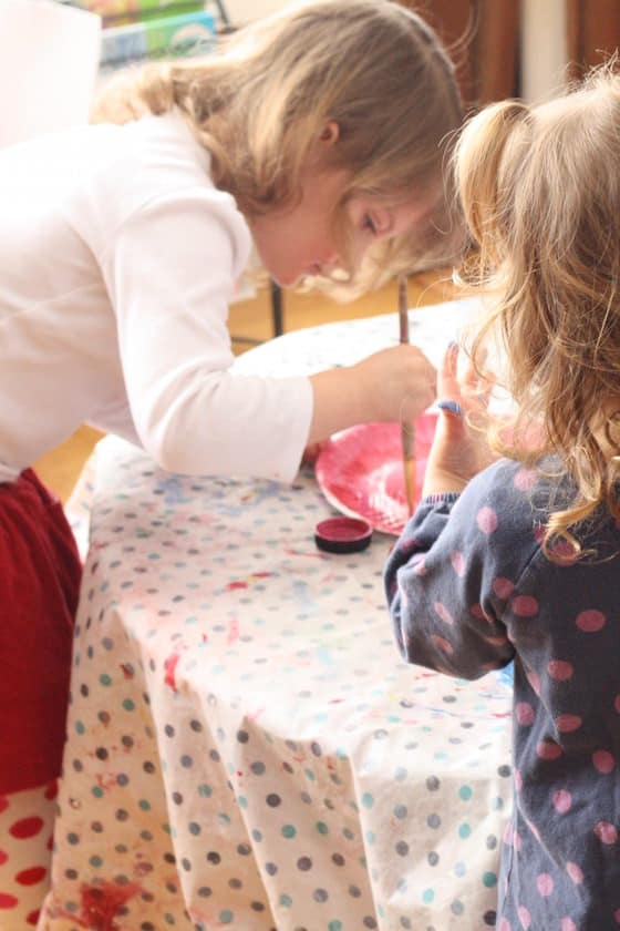 2 preschoolers painting red paper plates