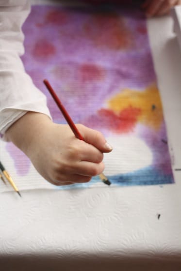 preschooler painting paper towel with watercolours