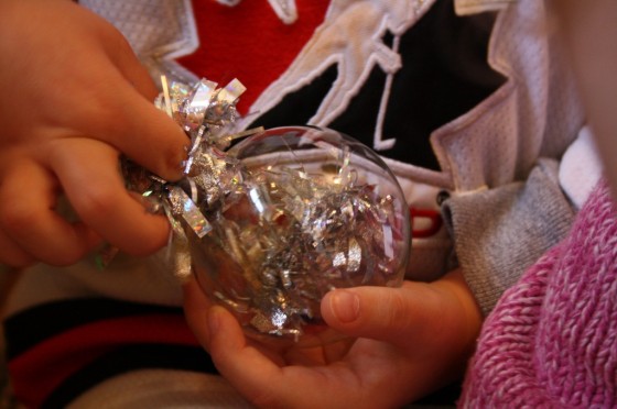 toddler filling clear glass Christmas ornament