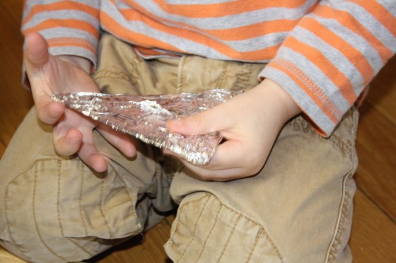 child wrapping cardboard with aluminum foil