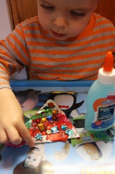 2 year old putting craft jewels on tree ornament