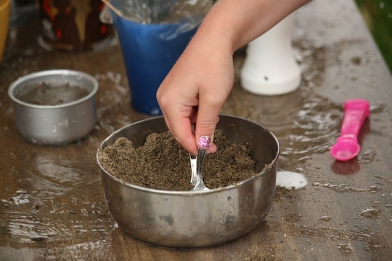 7 year old scooping sand as pretend coffee grounds