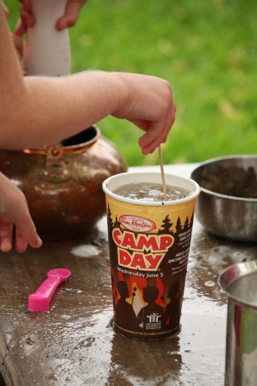 preschooler stirring water and sand in take out coffee cup