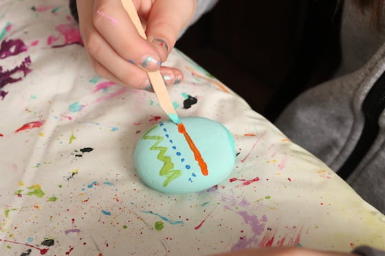 Kid painting rock to look like Easter Egg