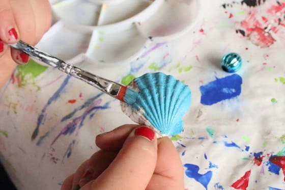 kid painting sea shell blue