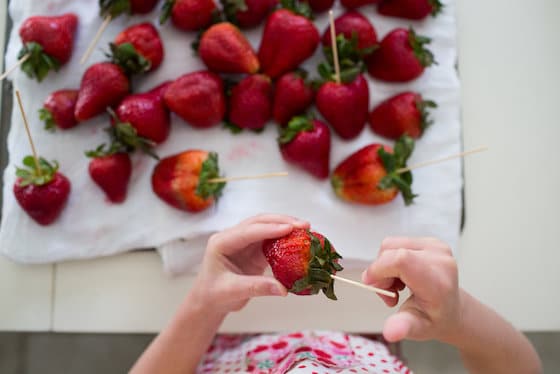 kid putting skewers into strawberries