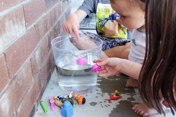 Kids adding toys to bucket of water to see if they sink or float