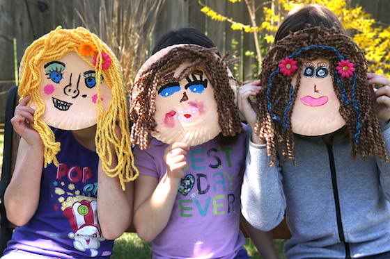 Kids holding up paper plate self portraits