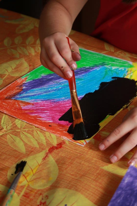 kids painting over pastels with black paint