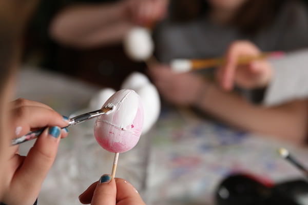 Kid priming plastic egg with Gesso