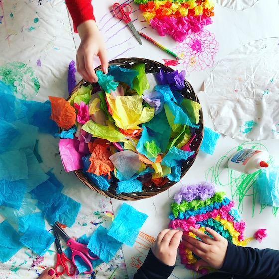 Kids reaching into basket of tissue paper scraps