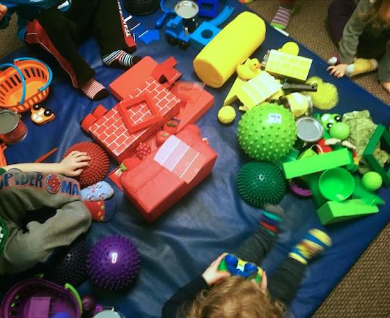 kids sitting in pile of coloured toys