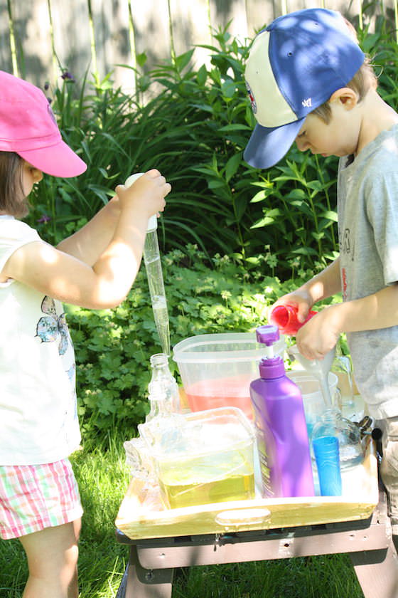 kids using basters to transfer coloured water into glass jars