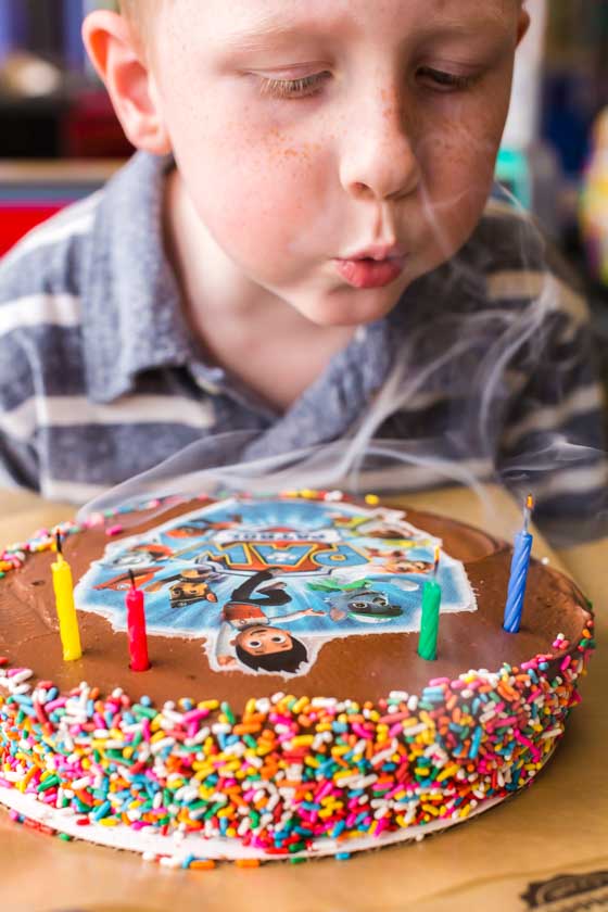 Little Boy blowing out candles on Paw Patrol cake at Chuck E Cheese