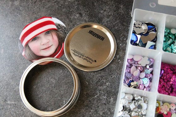 Mason jar lid, photo of child, container of beads and gems