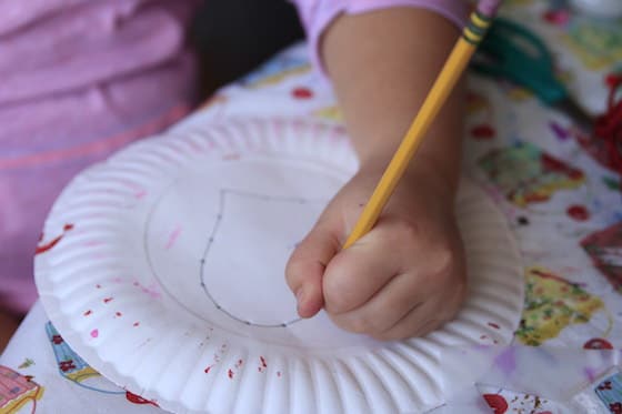 Kid poking holes in a paper plate