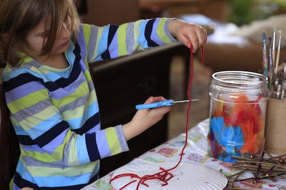 5 year old cutting red yarn with scissors