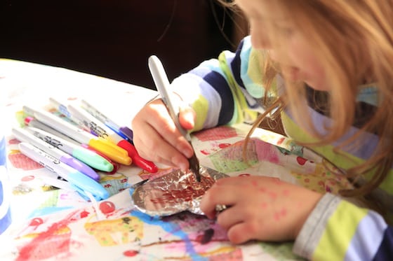 Child colouring on tinfoil with a Sharpie marker