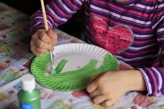 Child painting paper plate green