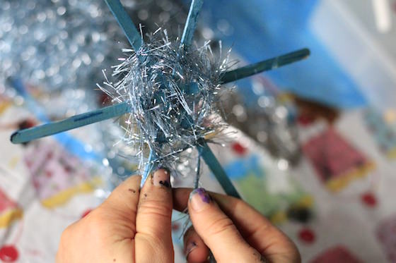 making snowflake ornament by weaving fuzzy yarn around craft sticks